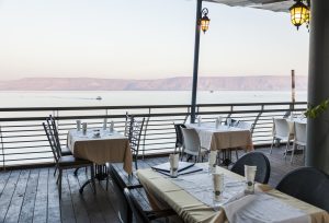 Restaurant tables on a veranda overlooking the Sea of Galilee in Israel.